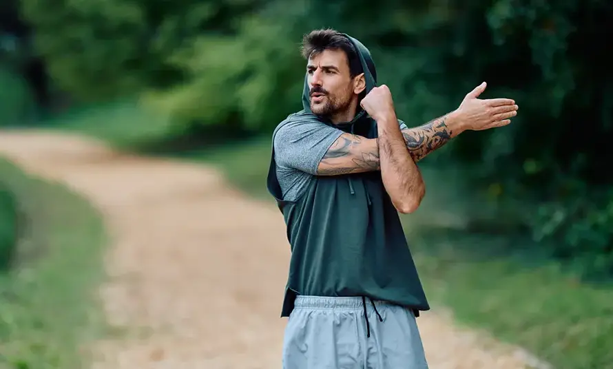 Man stretching arm before working out in park stock photo