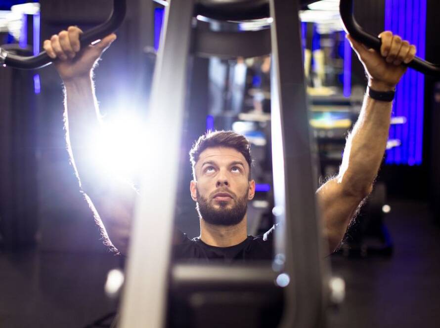 Young man lifting weights in a modern gym during a workout session at night stock photo